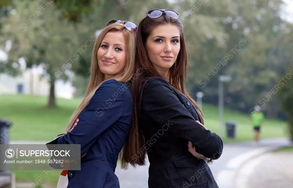 Two young women standing back to back