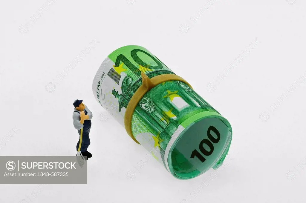 Miniature figure of a workman standing in front of roll of 100-euro notes and looking thoughtfully up