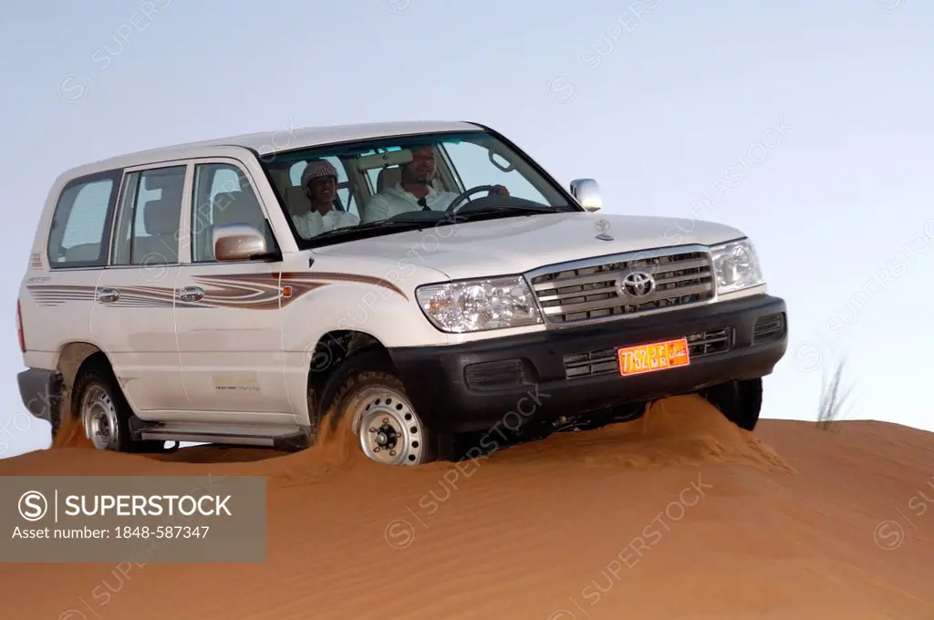 Toyota pickup truck drives on a sand dune in the Wahiba Sands, Al Ramlat Wahaybah, Sultanate of Oman, Middle East
