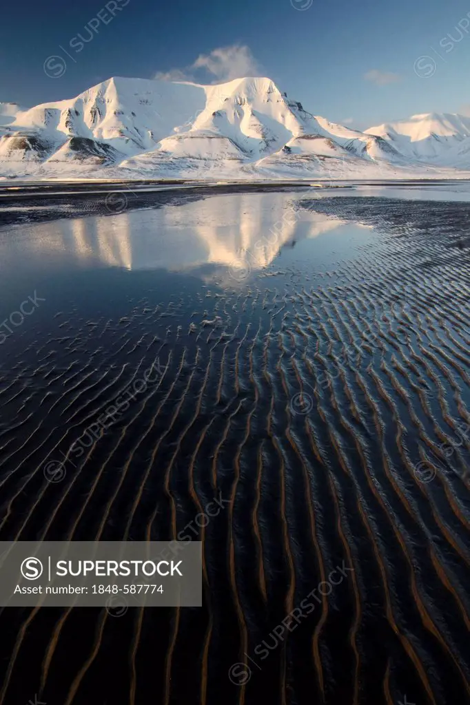 Hjorthfjellet, home mountain of the town of Longyearbyen, is reflected in the wintry mud flats, Spitsbergen, Svalbard, Norway, Europe