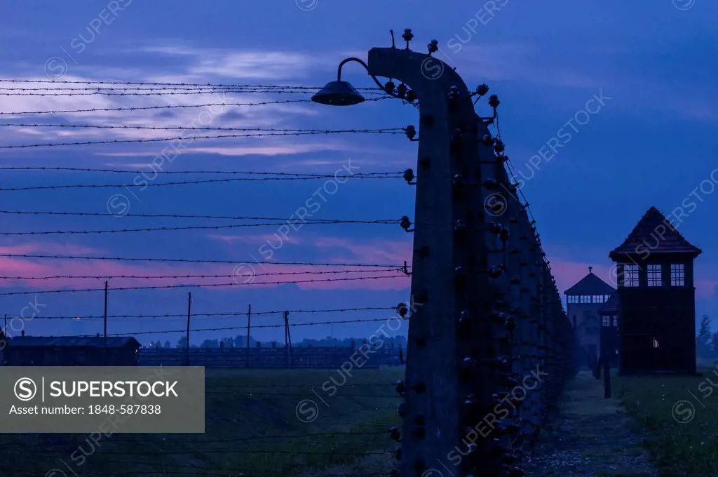 Barbed wire fence, watchtower and barracks at dusk, night, Auschwitz-Birkenau concentration camp, Auschwitz, Lesser Poland, Poland, Europe