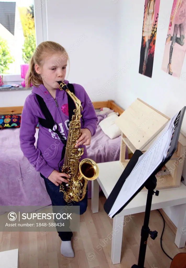 Girl, 10 years, practising saxophone in her room