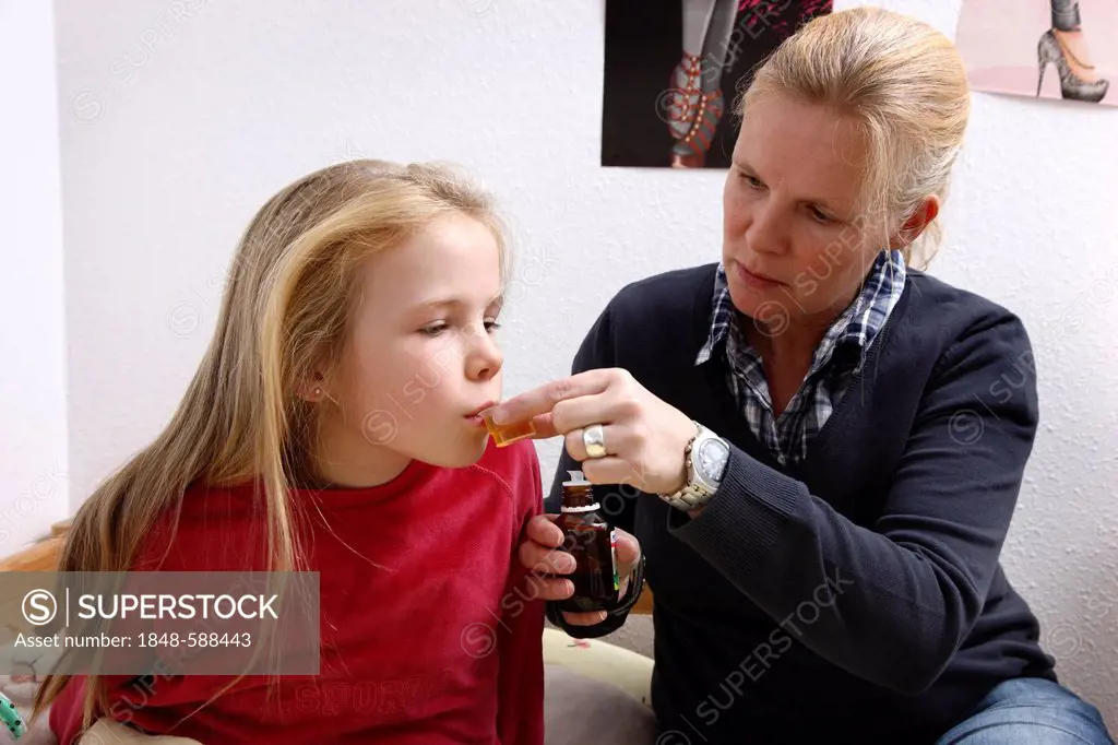 Girl, 10 years old, with a cold, flu, fever, cough, her mother is giving her cough syrup