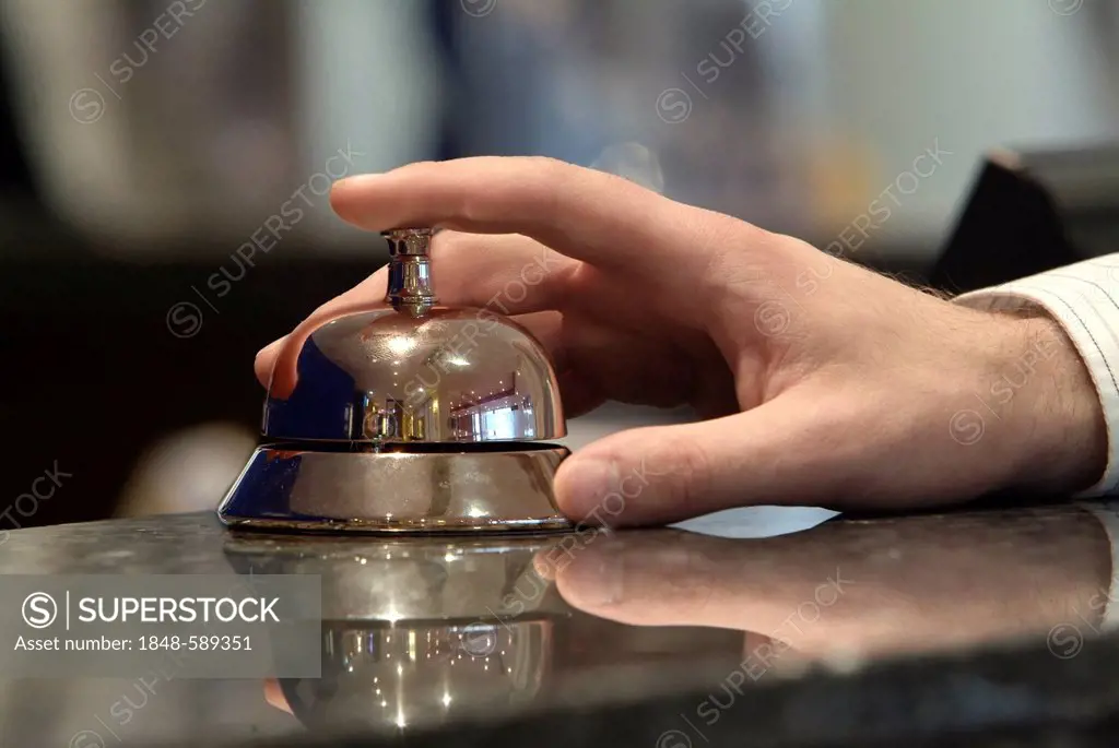 Hand resting on a hotel reception bell