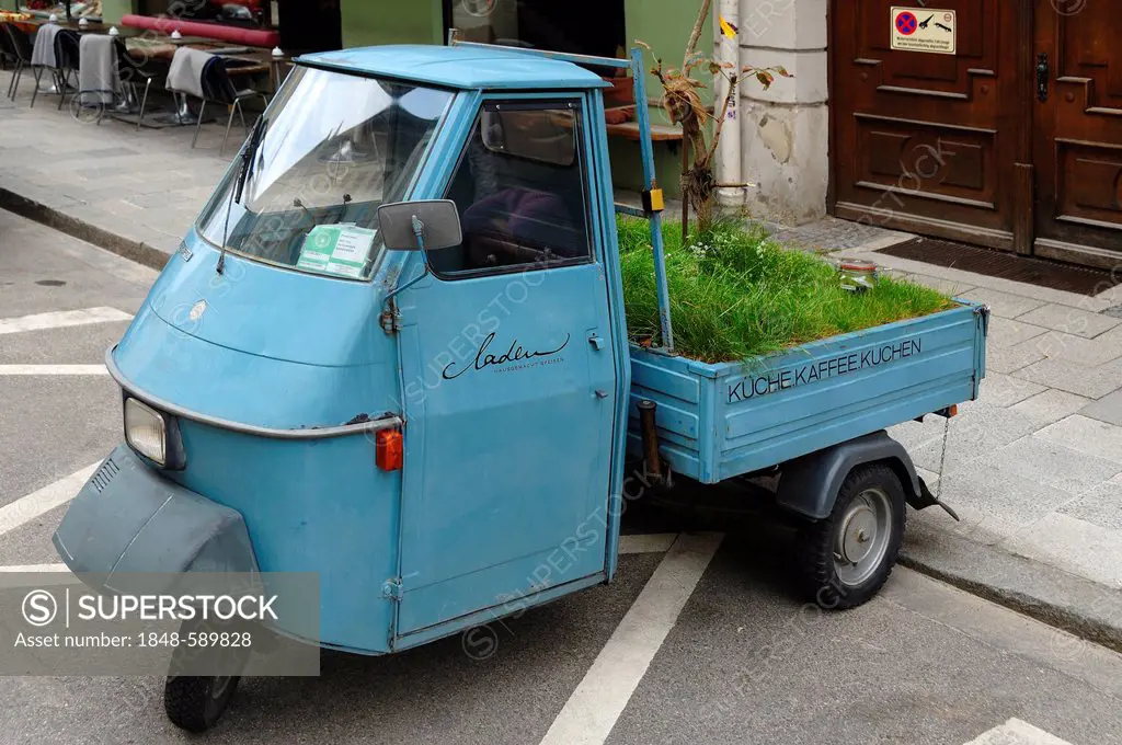 A three-wheeled Piaggio from 1978 as an advertisement in front of a cafe in Munich, Bavaria, Germany, Europe