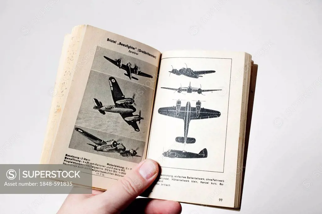 A man's hand holding a book about aircraft recognition with war planes from World War II, published by Dr. Spohr Verlag, 1942, Dresden, Germany, Europ...