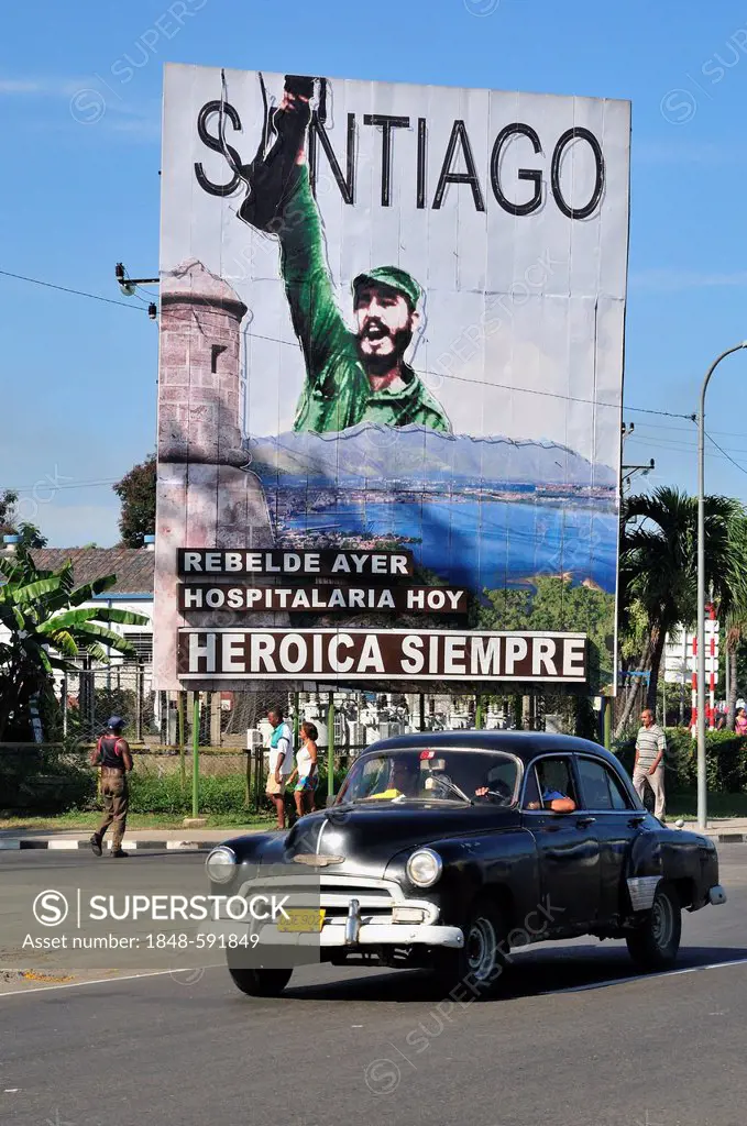 Vintage car driving in front of revolutionary propaganda poster, Santiago siempre heróica, Spanish for Santiago is always heroic, Plaza de la Revoluci...