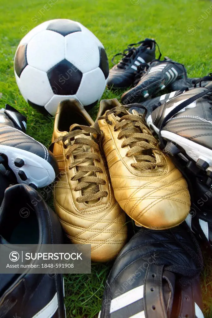 Black and gold football boots with a football