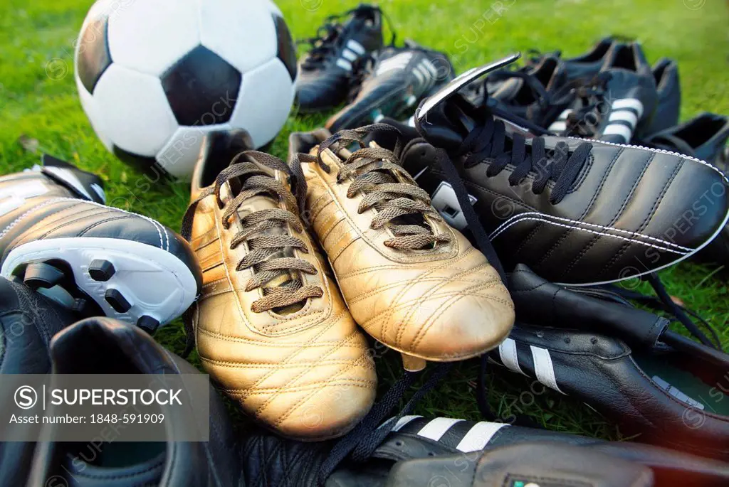 Black and gold football boots with a football