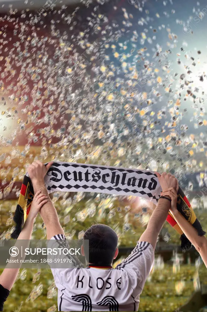Football fan holding up a German supporters scarf, seen from behind, with confetti in a football stadium