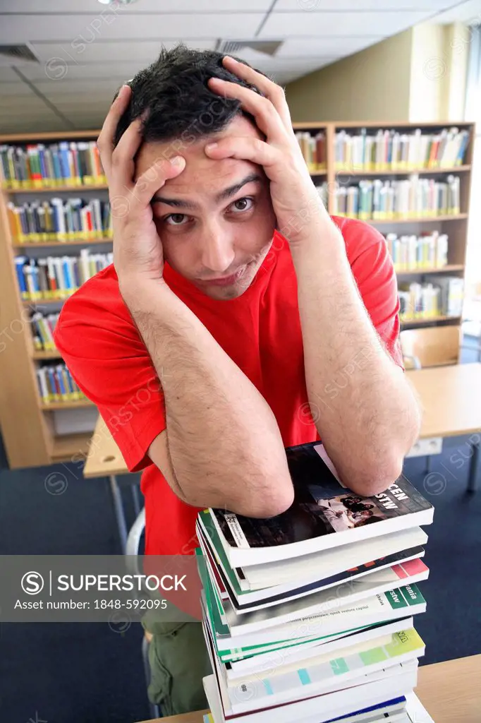 Desperate student with a stack of books in a university library