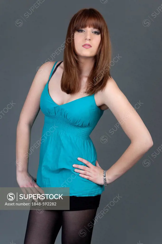 Young woman in a turquoise top posing with self-confidence