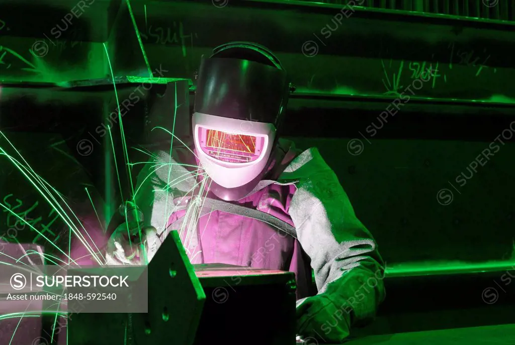 Welder wearing protective clothing in a steel mill