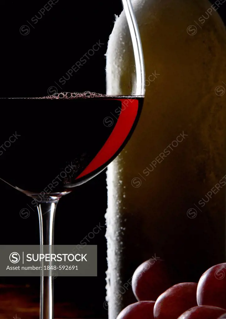 Red wine glass, wine bottle and grapes