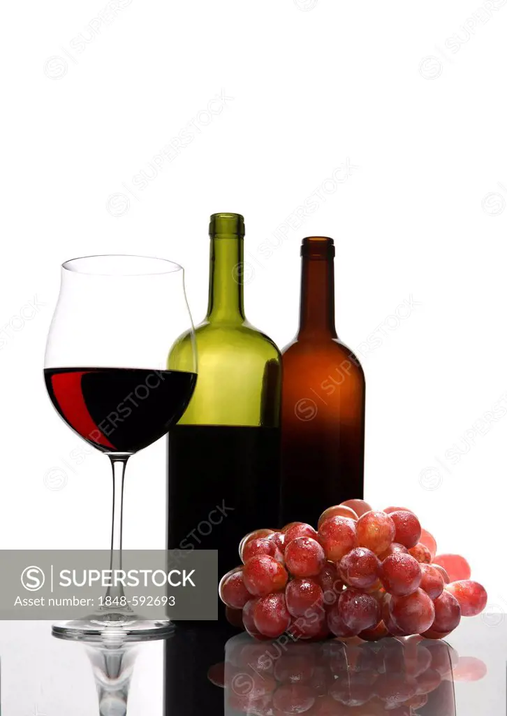 Red wine glass, wine bottles, grapes