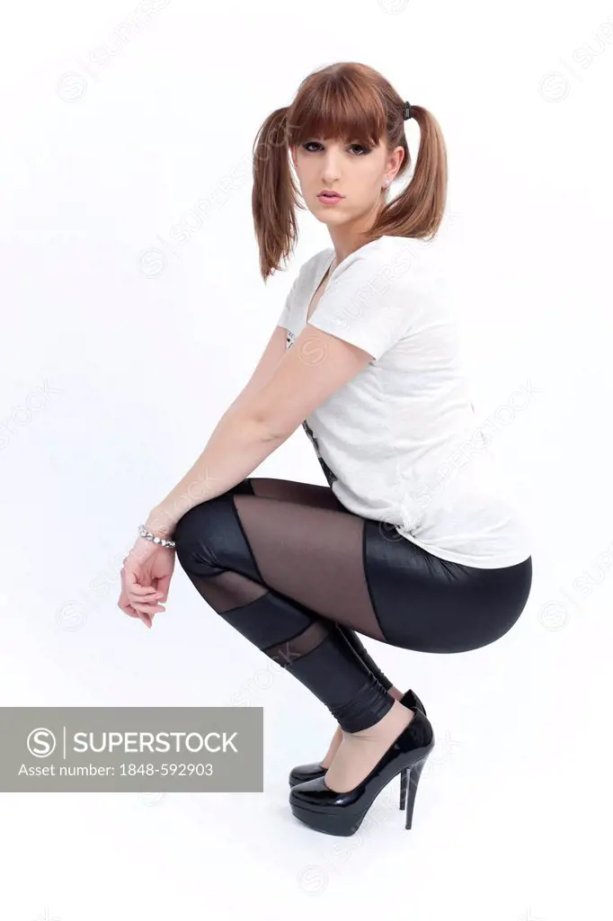 Young woman with pigtails posing in a squatting position
