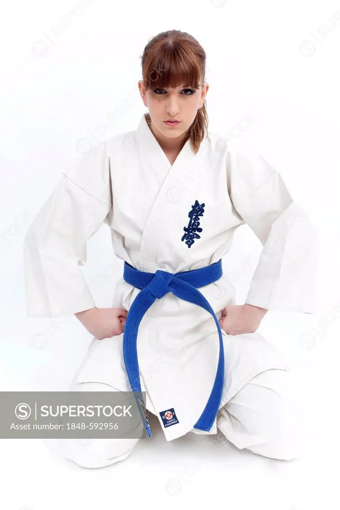 Young woman in a karate robe with a blue belt kneeling