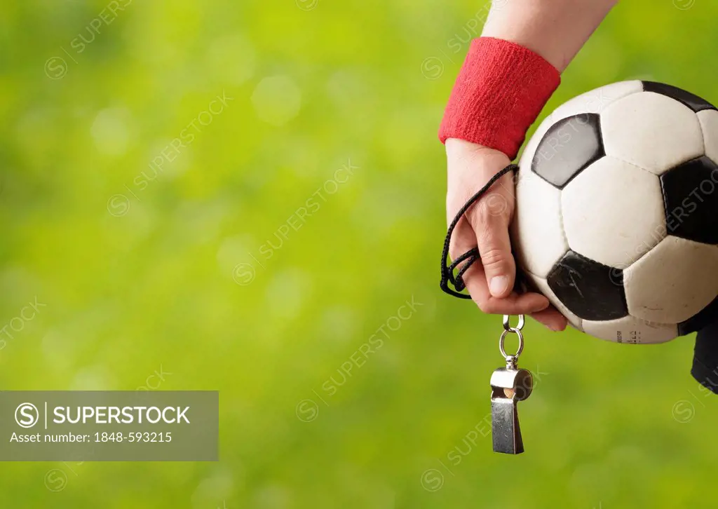 Referee with a sweatband and a whistle holding a football