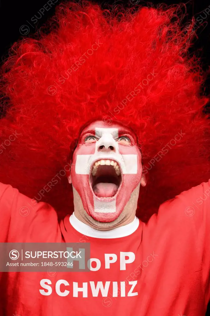 Screaming young man, football fan with a painted face, Swiss national flag, wearing a red t-shirt, lettering Hopp Schwiiz, German for Go Switzerland