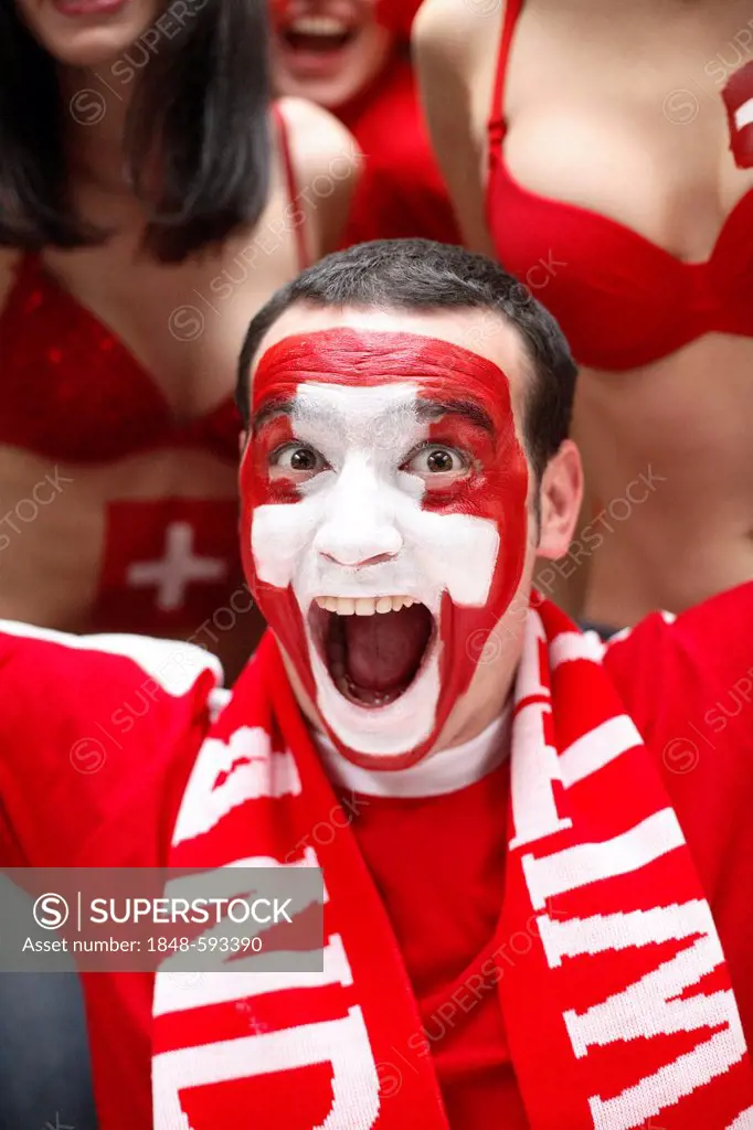 Screaming young man, football fan with a painted face, Swiss national flag