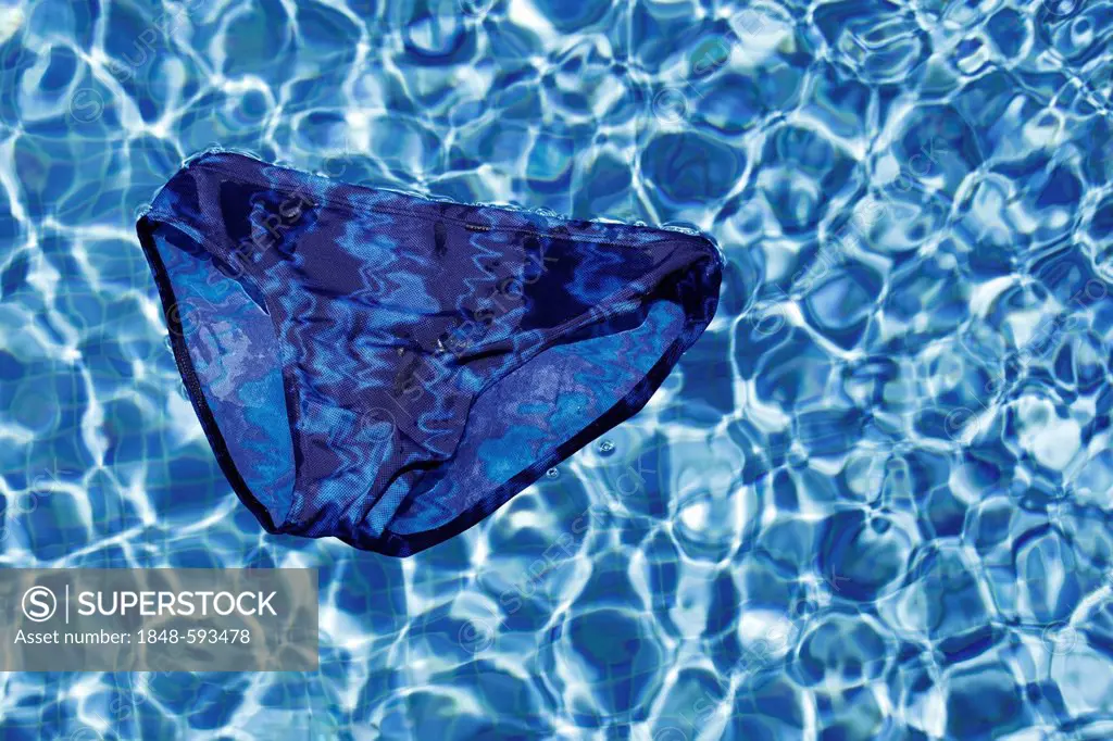Blue swimming trunks floating on the surface of a swimming pool, symbolic image for vacations or holidays