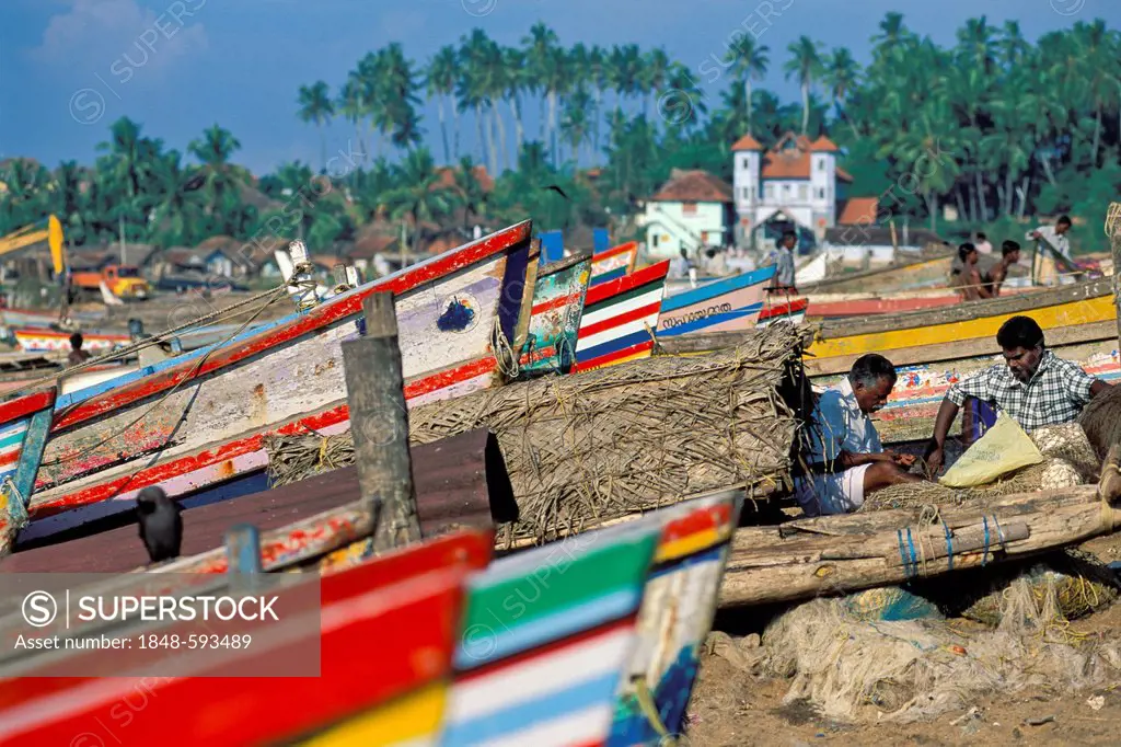 Fishermen mending nets, coloured fishing boats, palm trees, Kovalam, Kerala, South India, India, Asia