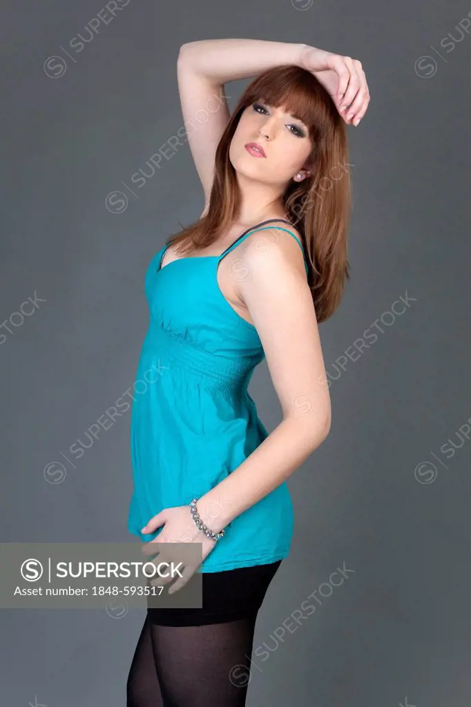 Young woman in a turquoise top posing with self-confidence