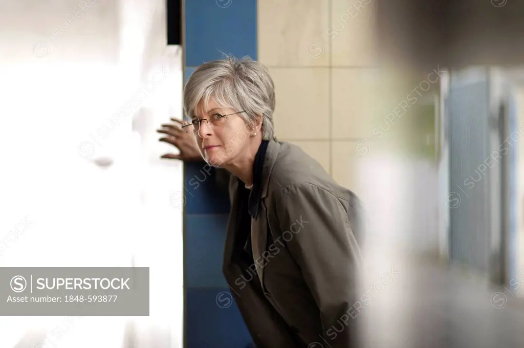 Woman looking carefully around the corner of a staircase