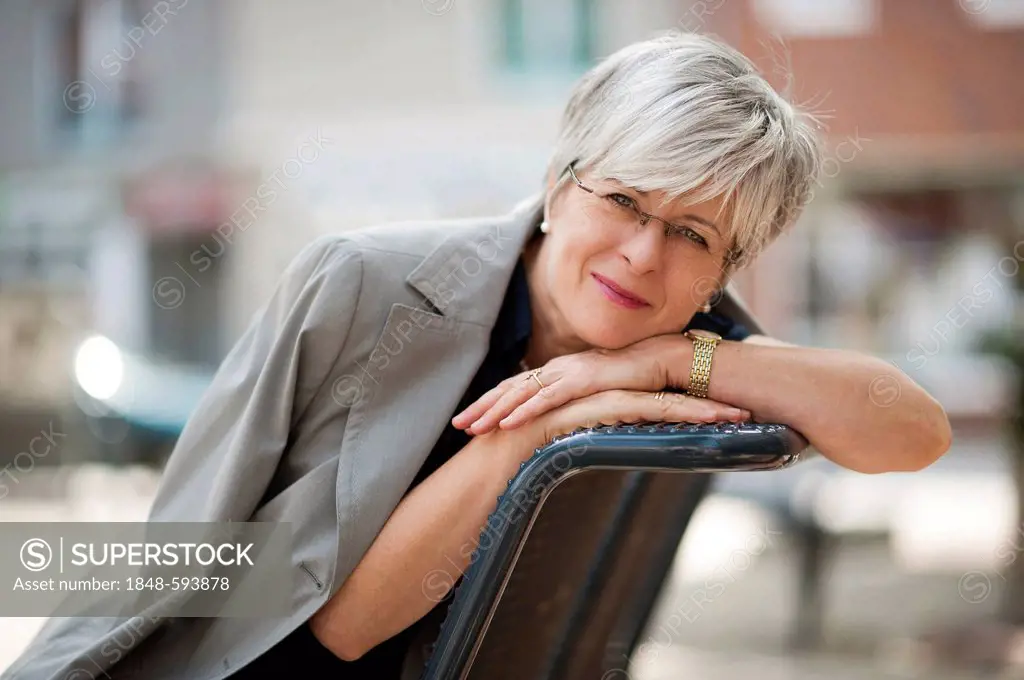 Woman, 50 +, sitting on a bench and smiling
