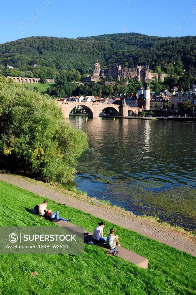 People at the Neckar river, at back the Alte Bruecke or Karl-Theodor-Bruecke bridge and the historic district of Heidelberg, Neckar valley, Baden-Wuer...