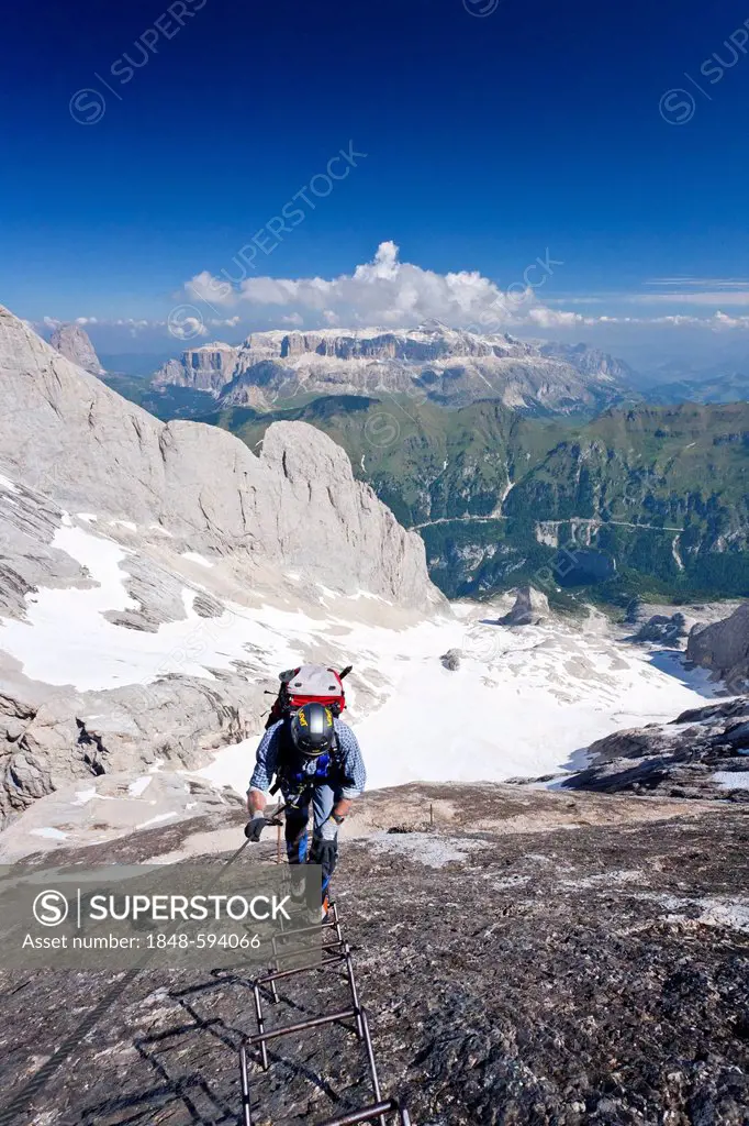 Mountain climber ascending Marmolada Mountain, Dolomites, in front of Sellastock Mountain, Fedaia Pass and Lake Fedaia, Westgrat climbing route, Trent...