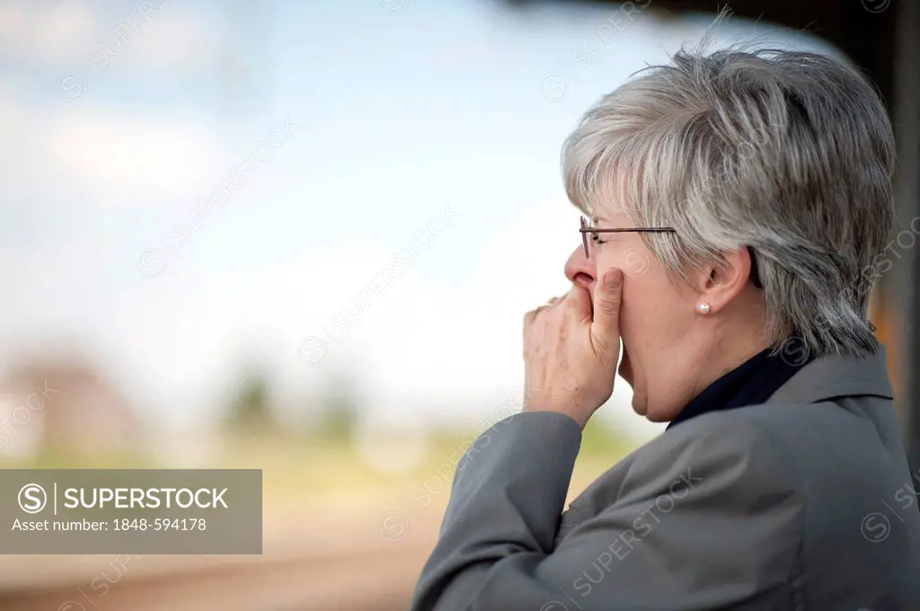 Woman, 50 +, yawning and holding her hand over her mouth