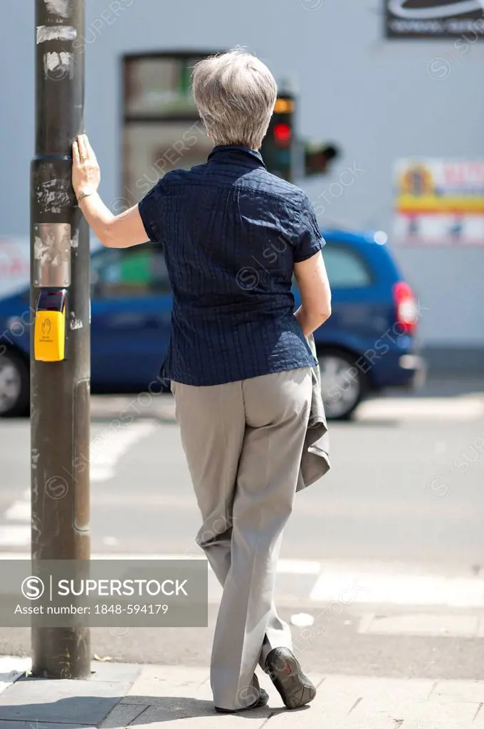 Woman, 50 +, waiting for the green light of a traffic light at an intersection