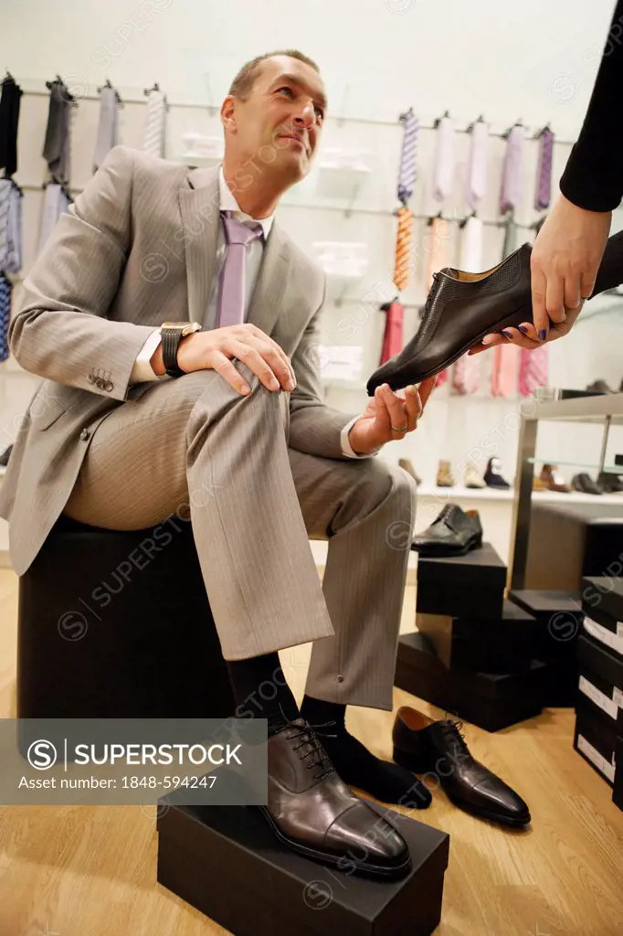 A man is trying on shoes in a men's outfitter