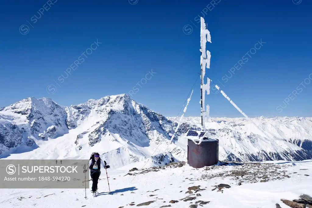 Cross country skier on the summit of Hintere Schoentaufspitze Mountain beside the weather station, looking towards the Ortler and Zebru Mountains, Sol...