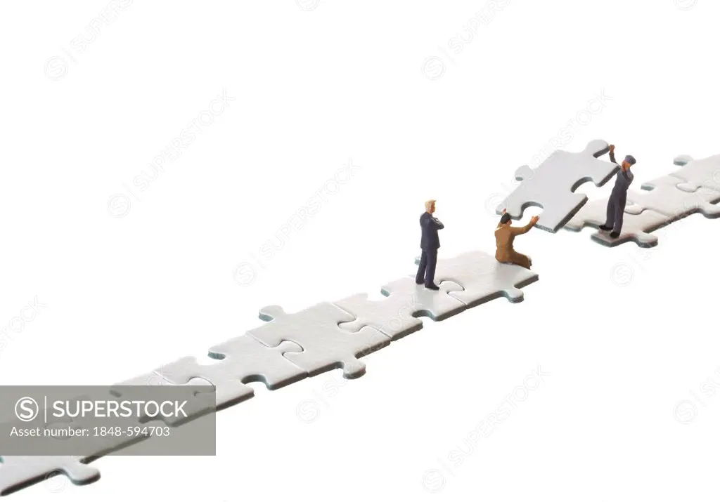 Figures of businessmen building a bridge with puzzle pieces, symbolic image for connections