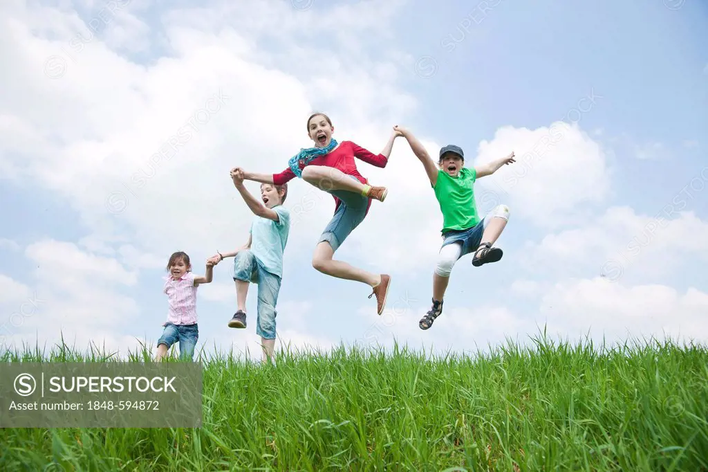 Four friends, three girls and a boy jumping into the air