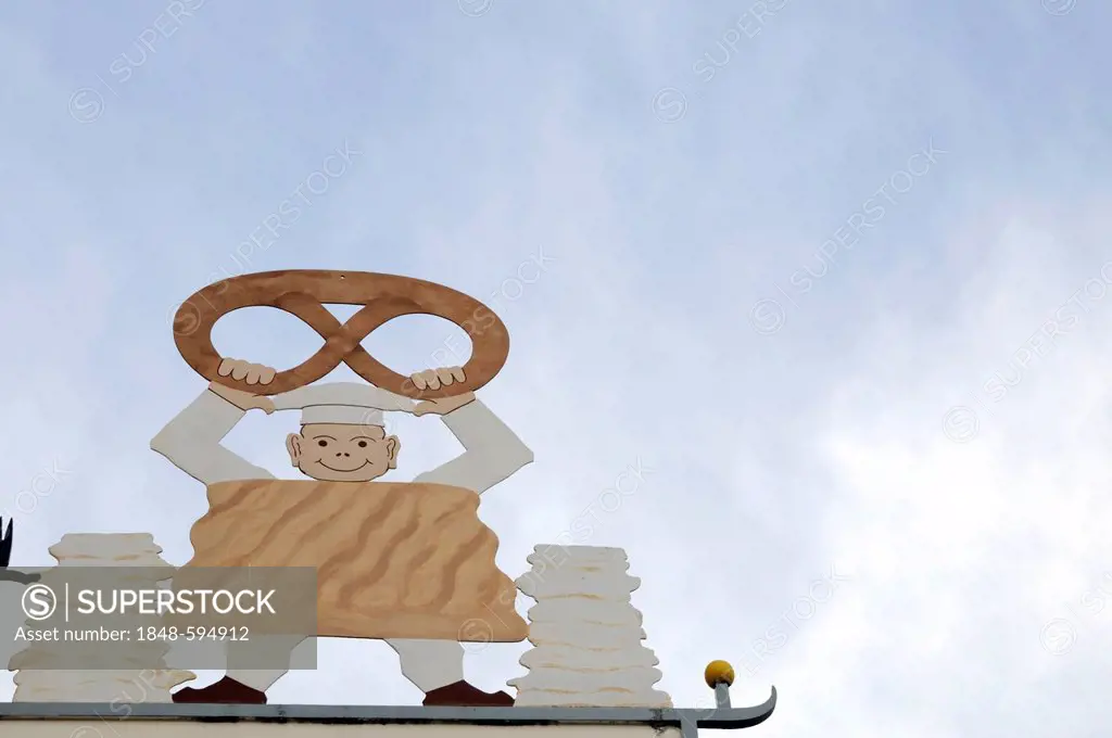 Sign of a bakery, figure holding a pretzel