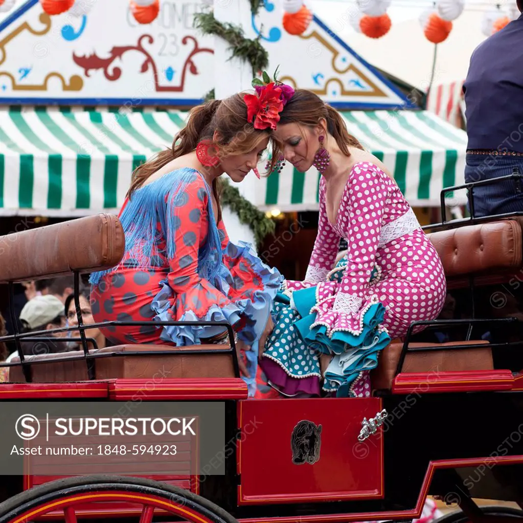 Two young women wearing flamenco dresses on a carriage at the Feria de Abril April Fair in Seville, Andalucia, Spain, Europe