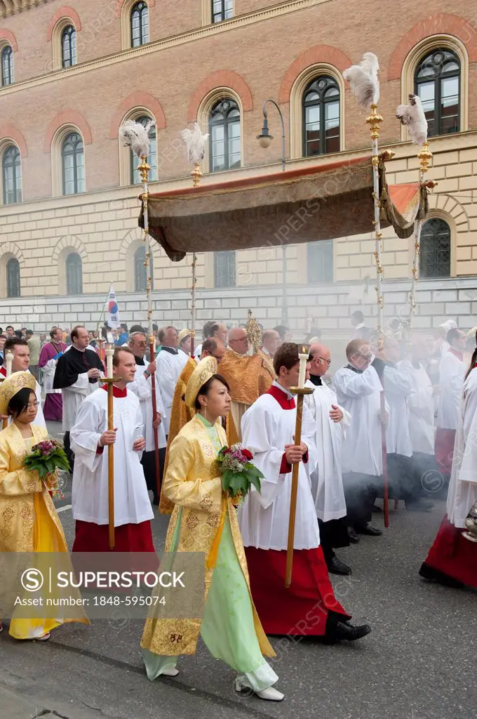 Catholic Corpus Christi procession, Archbishop Reinhard Marx carrying the monstrance with the Blessed Sacrament under a canopy, altar boys and religio...