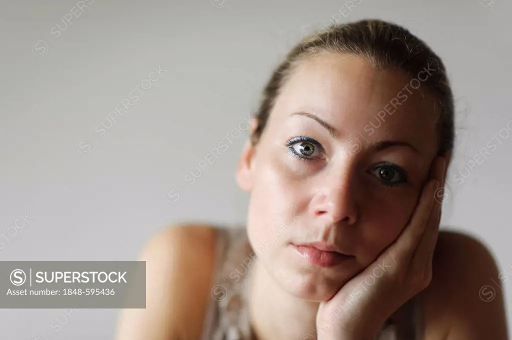Thoughtful young woman with her head in her hand, portrait