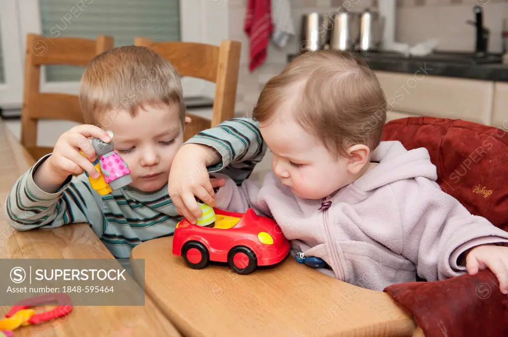 Two children, 3 and 1 years, playing together with a toy car