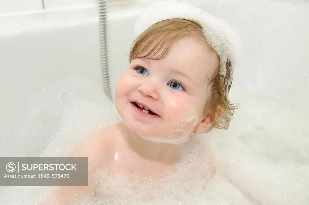 Girl, 1 year, playing with foam in the bathtub, portrait