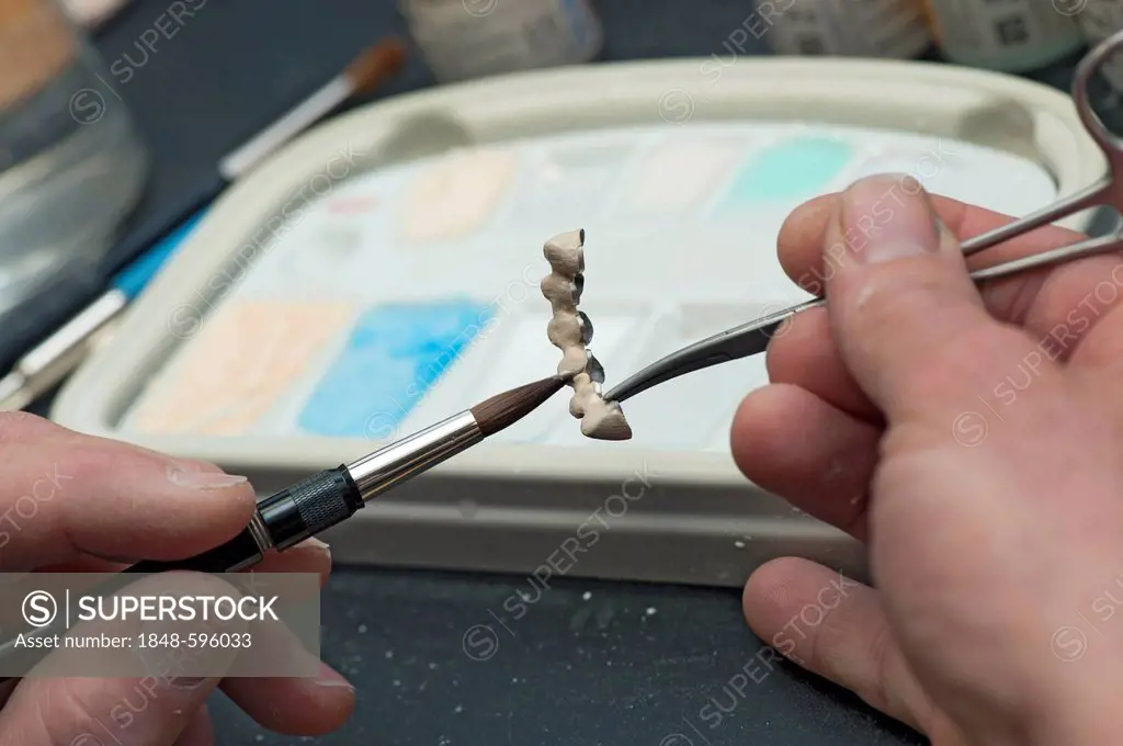 Ceramic layers being applied onto tooth crowns with a brush