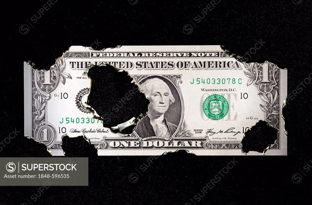 U.S. dollar bill with burn holes, symbolic image for the national debt of the USA