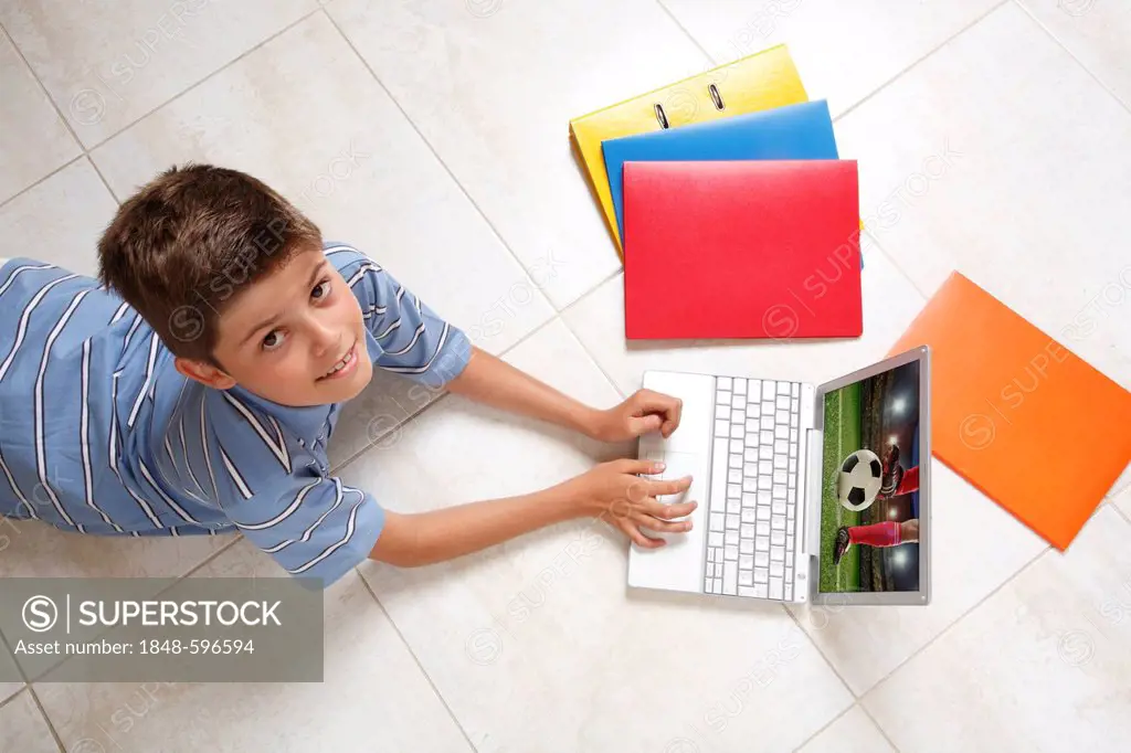 Young looking up while lying on the floor with a notebook, folders, and files