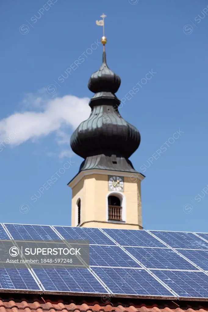 Solar panels on the roof of a house in front of the Church of the Nativity, Frauenried, Irschenberg district, Upper Bavaria, Bavaria, Germany, Europe