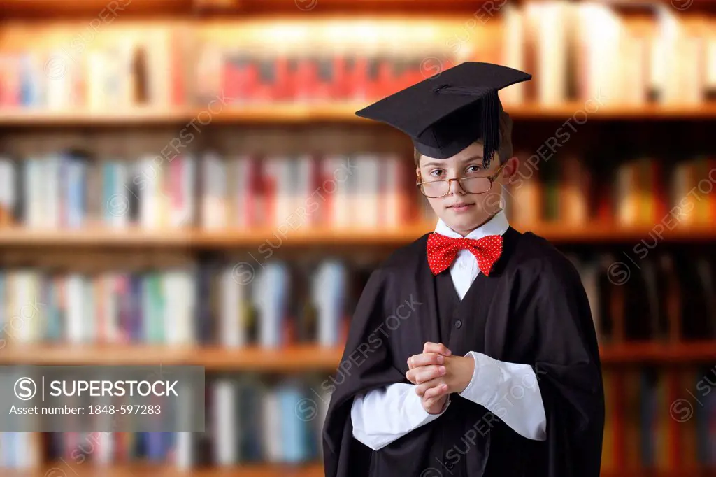 Schoolboy wearing a graduation cap in a library