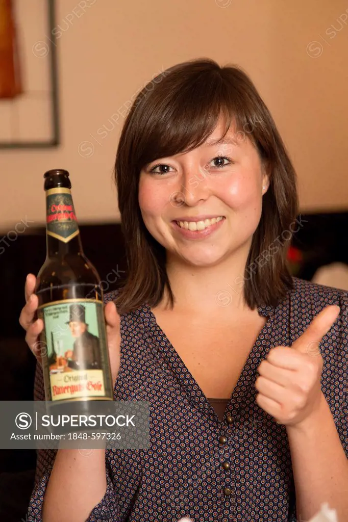 Woman holding a bottle of Gose beer, thumbs up gesture, Barthelshof restaurant, Leipzig, Saxony, Germany, Europe