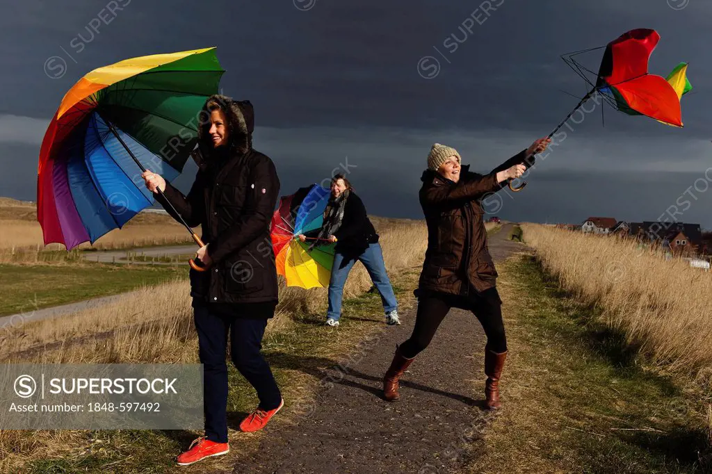 Three women holding umbrellas, stormy weather, Sankt Peter-Ording, Schleswig-Holstein, Germany, Europe